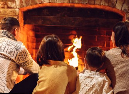 Family warming up beside a brick fireplace in Westchester